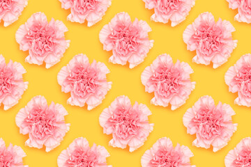 Pattern made of pink carnation flower on a yellow background.