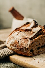 Vertical shot of a loaf of fresh bread on a wooden board