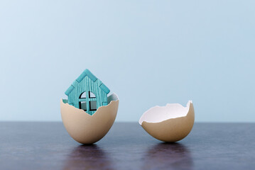 House in egg shell over light blue background with copy space. Conceptual Easter greeting card - 589109442