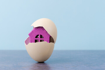 Pink House in egg shell on blue background with copy space. Conceptual Easter greeting card