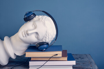 The concept of listening to an audiobook, literary podcast. The plaster head of the beautiful...