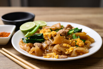Thai food (Pad See Ew), Stir fried rice noodles soy sauce with pork, egg and kale on wooden background