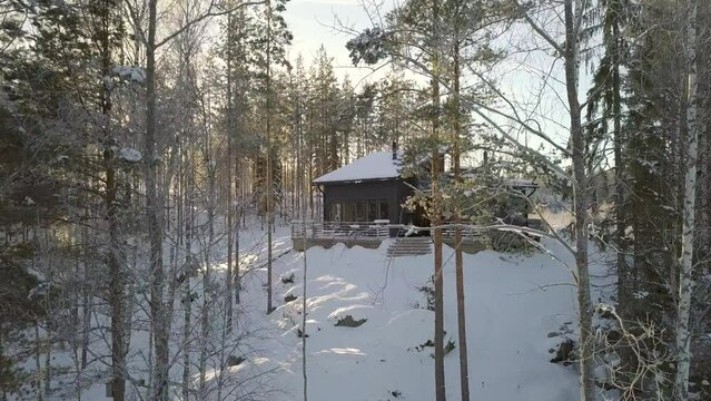 Circular aerial view of a lodge in the forest in a muffled atmosphere with snow.