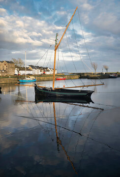 Old wooden fishing boat named Galway hooker reflected in water at Claddagh, Galway City, Ireland 