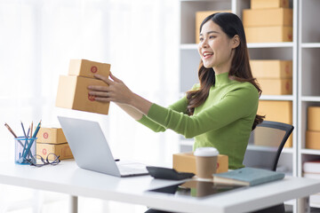 Startup SME small business entrepreneur freelance Asian woman using a laptop with box merchant seller checking customer address order confirming parcel SME delivery idea concept.