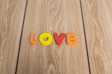 Closeup shot of colorful wording "LOVE" in capital letters on wooden background. Background picture of valentine theme. 