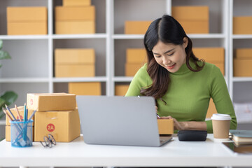 Startup SME small business entrepreneur freelance Asian woman using a laptop with box merchant seller checking customer address order confirming parcel SME delivery idea concept.