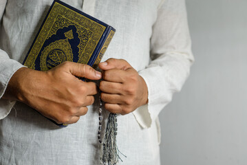 Man Holding the holy quran. Islamic Background. Arabic text on the cover translated with Al Quran
