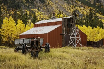 Red wooden barn and old tractor surrounded by yellow aspen trees in the countryside in Colorado © Christopher Loffredo/Wirestock Creators