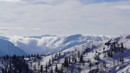Wolken kriechen &uuml;ber beschneiten Berg 