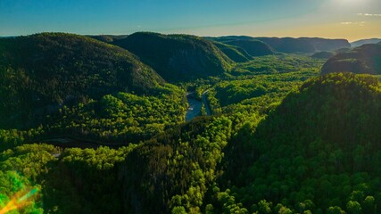 Fototapeta na wymiar Narrow river in Sainte-Marguerite Valley Forest at sunset in Quebec, Canada