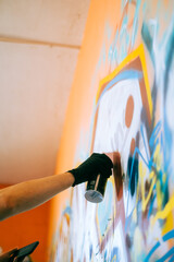 Young caucasian man graffiti artist drawing on a wall.