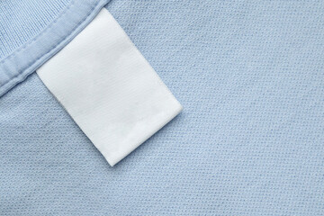 White blank laundry care clothes label on blue shirt fabric background