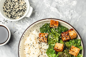 Vegan tofu poke bowl with rice and broccoli on a light background. Clean eating, dieting, vegan food concept. top view