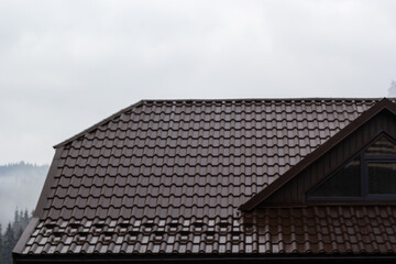 House with new brown metal tile roof and rain gutter. Metallic Guttering System, Guttering and...