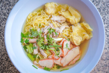 Egg noodles and pork wonton soup with red roasted pork, and crab meat dumplings, vegetables are delicious street food in Thailand.