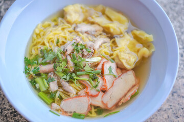 Egg noodles and pork wonton soup with red roasted pork, and crab meat dumplings, vegetables are delicious street food in Thailand.