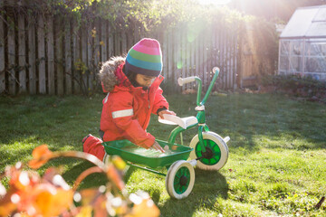 Girl (4-5) with tricycle in garden