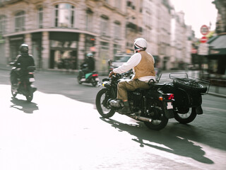 Horizontal photo of a man riding by the streets of Paris with an old retro vintage black motorbike with a sidecar, photo with motion blur