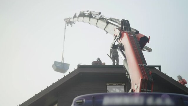 Crane extended arm with construction site bin over the house roof 4K