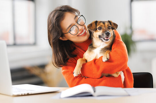 happy woman freelancer working on laptop remotely from home together with pet dog