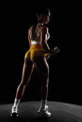 Fototapeta na wymiar Brutal sports woman pumps up muscles with dumbbells. Fitness concept.