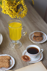 Cup of tea, plates with cookies, glass of orange juice, books, reading glasses, bowl of fruit and candles on the table. Selective focus.