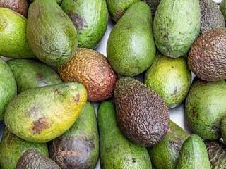 Ripe juicy avocados top view closeup, for sale at the local market. Fresh fruit colorful background.