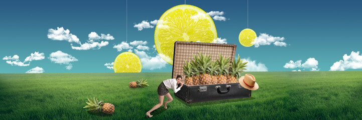 Tropical travel. Young girl pushing retro suitcase with pineapples on green field. Vacation time....