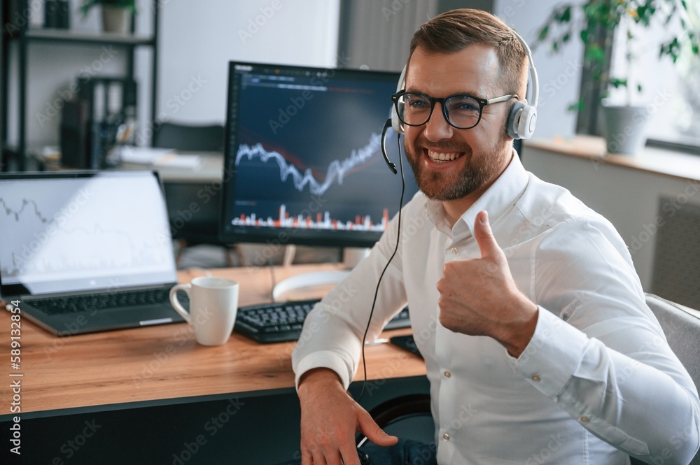 Poster stock exchange graphs on the screen. man in formal clothes is working in the modern office. using co