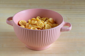 Corn flakes in pink soup bowl. Breakfast Cereal