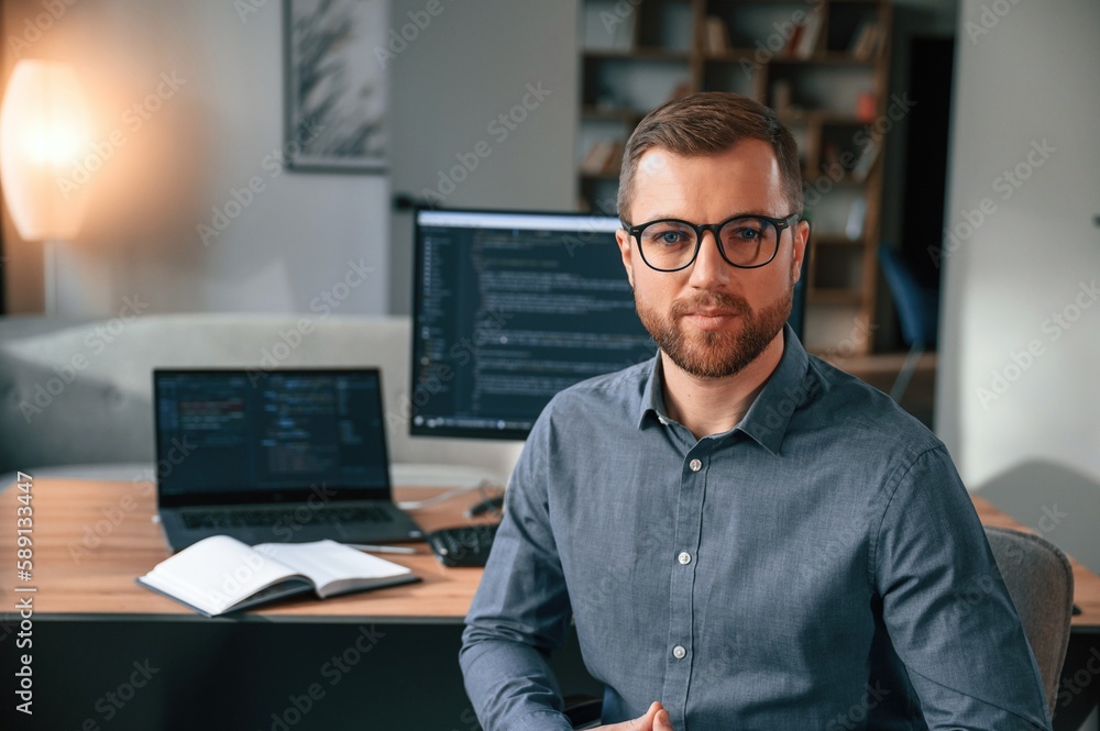 Poster software developer is sitting and posing. man in formal clothes is working in the modern office. usi