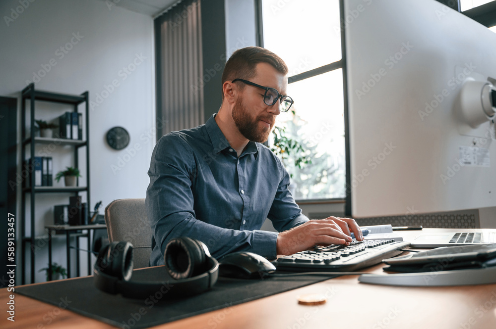 Poster typing on the keyboard. man in formal clothes is working in the modern office. using computer