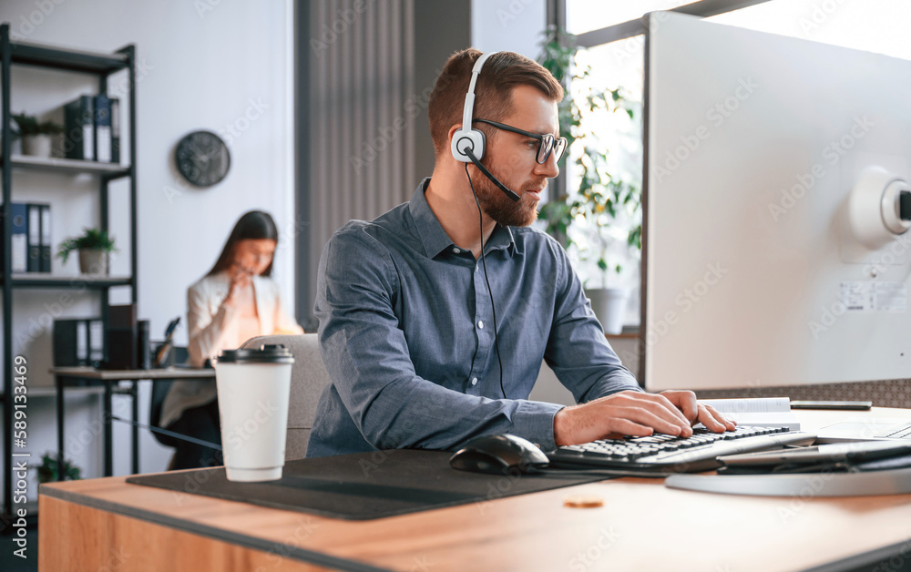 Poster man is using computer. two employees are working together in the modern office