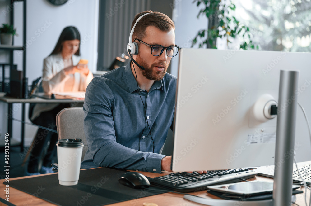 Poster man is using computer. two employees are working together in the modern office