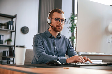 Obraz premium Typing on the keyboard. Man in formal clothes is working in the modern office. Using computer