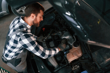 Fototapeta na wymiar Car details. Repairing the vehicle. Man in uniform is working in the auto salon