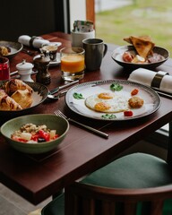 Delicious breakfast set on a wooden table with eggs, croissants, oatmeal and salad