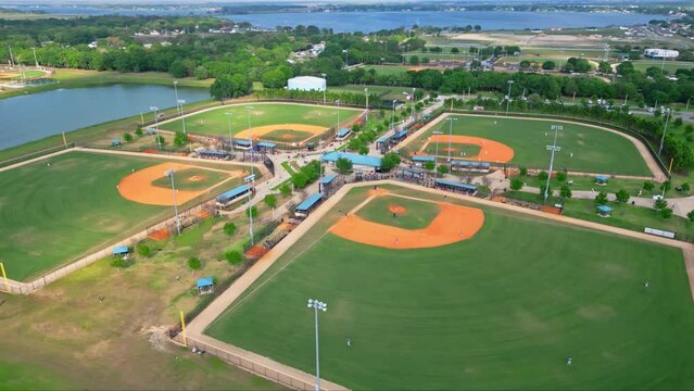 Orbit Shot Of Four Green American Baseball Courts Near Blue Sea At Evening Time, Florida