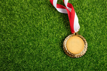 Gold medal with ribbon on green grass background, concept of victory or success. - 589143057
