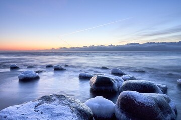 Closeup of rocks covered in the frost and ice in a frozen river under a cloudy sky