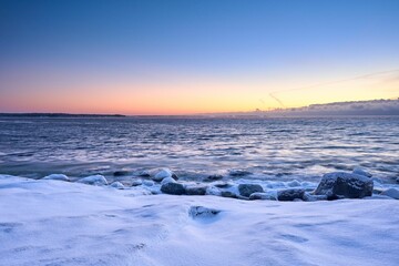 Fototapeta na wymiar Aerial view of sea waves breaking snow covered beach during sunset