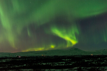 imagen de un paisaje nocturno nevado, con una aurora boreal en el cielo nocturno de Islandia  - obrazy, fototapety, plakaty