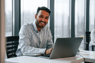 Beautiful indian man is working in the office by laptop