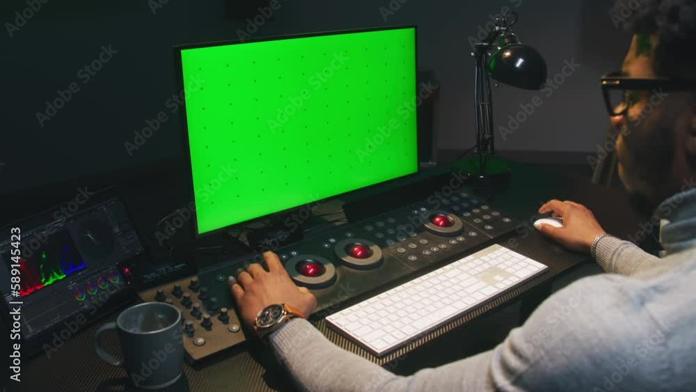 Poster african american film maker works on computer in studio with digital equipment. color grading contro