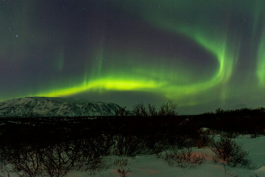imagen nocturna de un paisaje nevado con una aurora boreal en el cielo nocturno de Islandia 