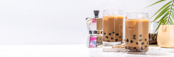 Iced tapioca coffee latte or boba pearl bubbles milk tea, asian trendy cold coffee drink with tapioca balls and crushed ice, on white marble background copy space