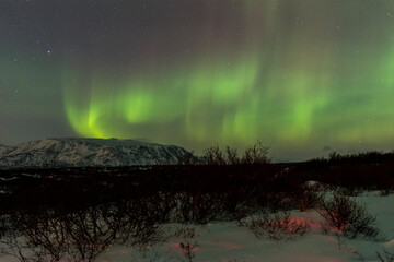 imagen nocturna de un paisaje nevado con una aurora boreal en el cielo nocturno de Islandia  - obrazy, fototapety, plakaty
