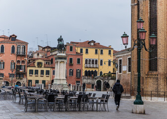 Square in Venice, Italy with restaurant and person walking by 