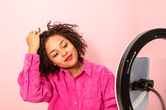 Calm ethnic woman demonstrating hairstyle during beauty tutorial